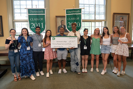 Alumni holding a check and smiling