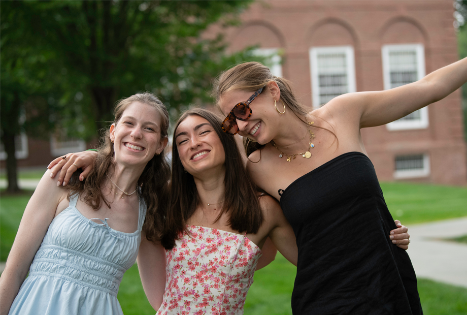 Three alumni smiling and hugging