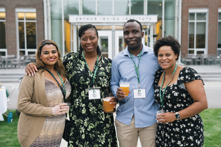 Alumni smiling and posing with drinks in hand