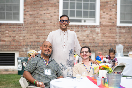 A person standing behind two people seated at a table. 