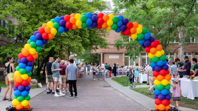 Rainbow balloon arch in front of people attending the DGALA dinner. 