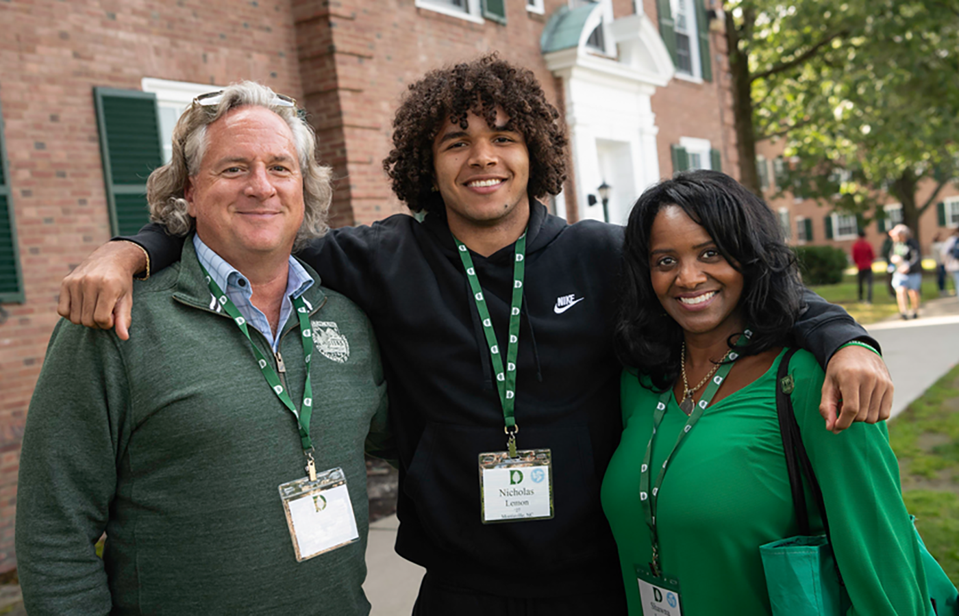 A male student with his arms around his parents.
