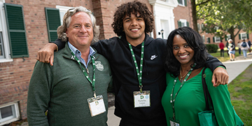 A male student with his arms around his parents.