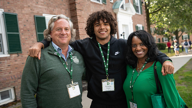 A male student with his arms around his parents.
