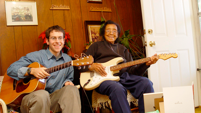 Mats Lemberger and Emma Baker seated, holding guitars and smiling