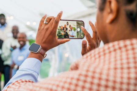 A person taking a photo of attendees with their iphone.