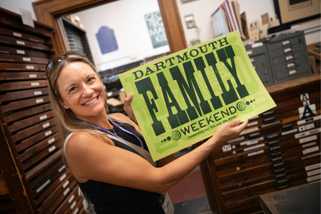 A person holding a print that says Dartmouth Family Weekend.