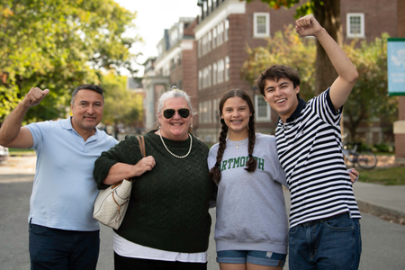 A family posing in a fun pose outside of a residence hall. 