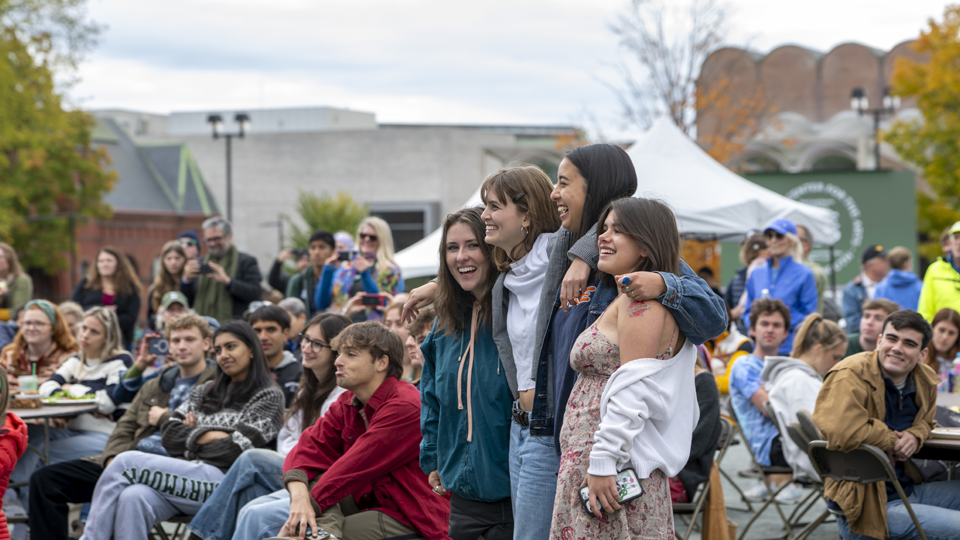 Girls smiling and hugging amidst crowd at community lunch