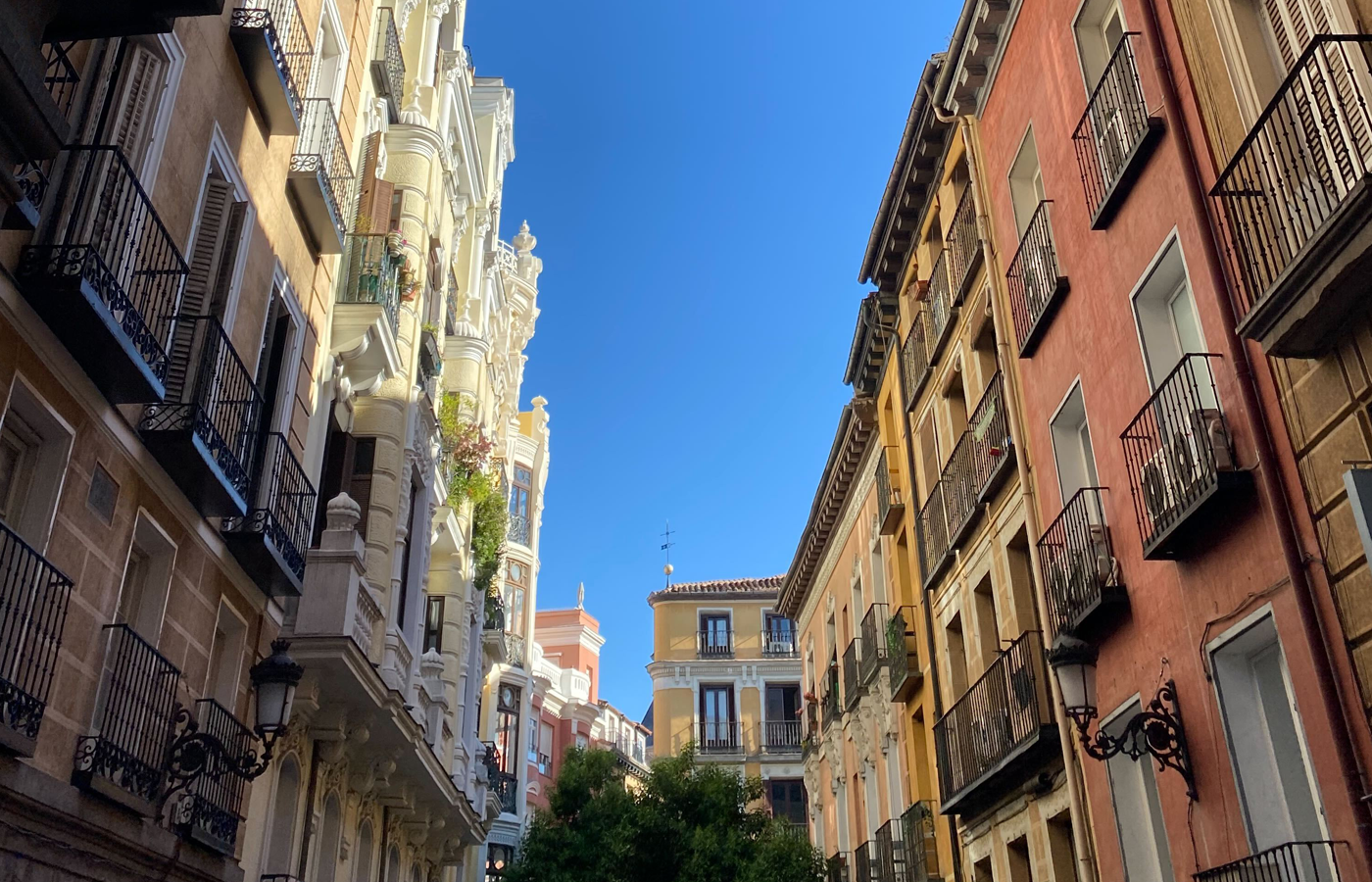 Shot along a Madrid street with colorful buildings lining it and a blue sky above