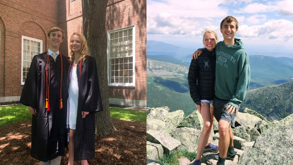 The couple in commencement regalia and posing on top of a mountain. 