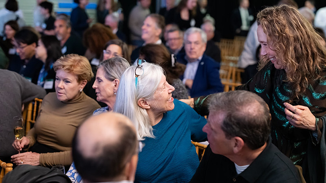 Two women greeting each other prior to the start of an evening program at an event