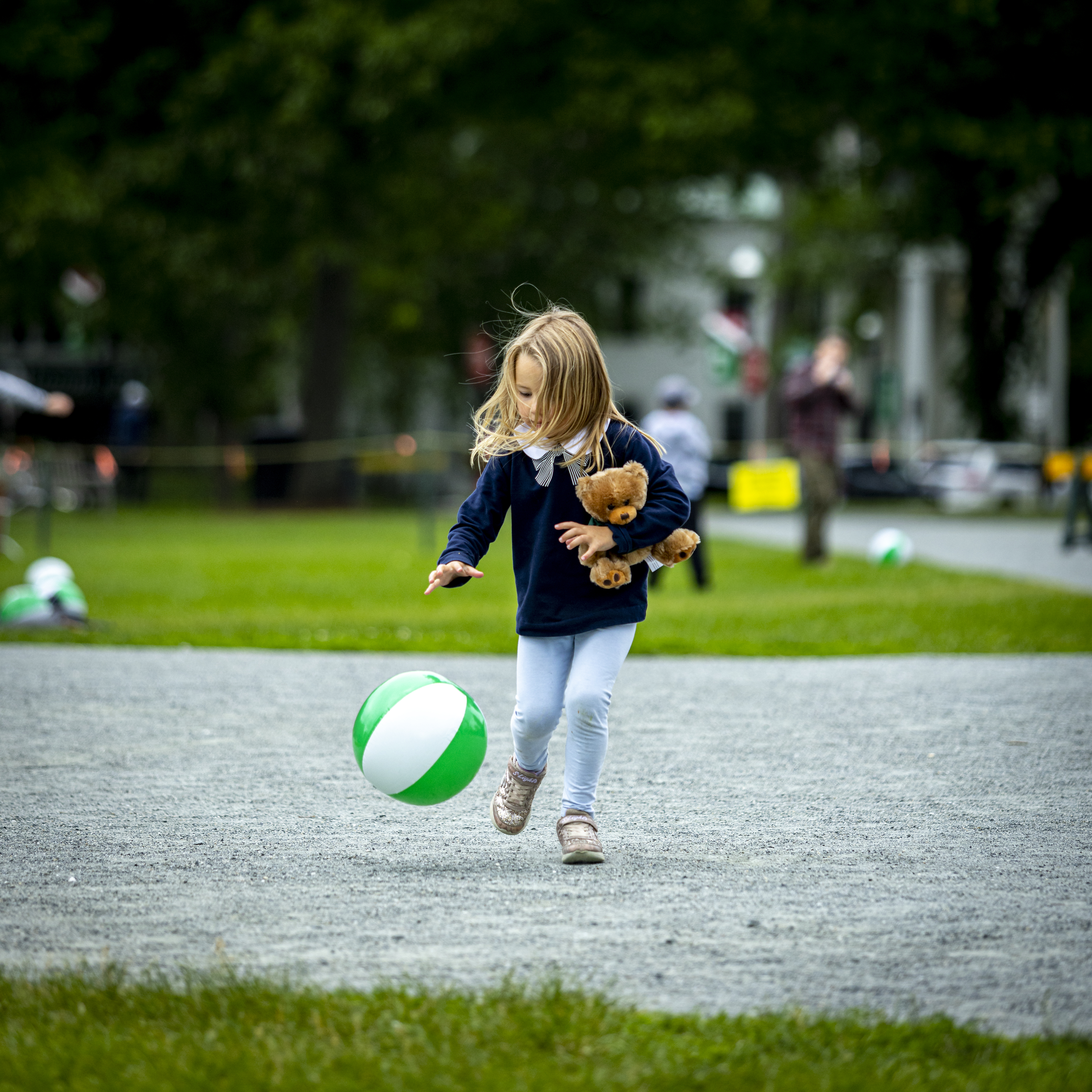 A toddler playing with a green and white ball on the Green