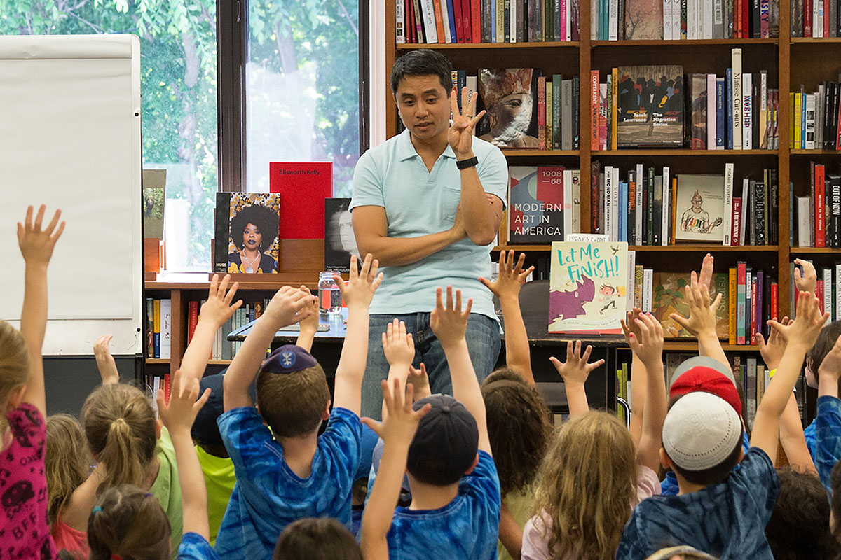 Minh Lê ’01 surrounded by young readers.