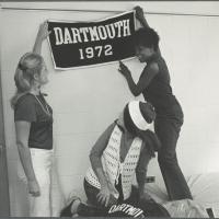 Dartmouth women in 1972 hanging a banner in a dorm room