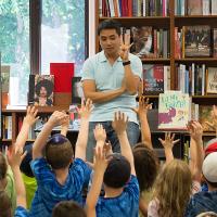 Minh Lê ’01 surrounded by young readers.