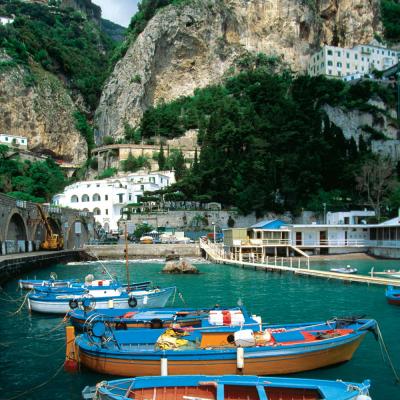 Blue fishing boats line the harbor of a small port along Amalfi Coast
